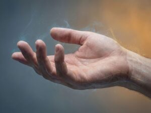 Hand met tintelende sensaties gevisualiseerd als lichtdeeltjes, op blauwe naar amber achtergrond symboliserend genezing