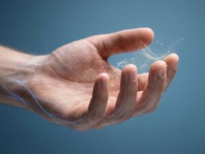 Menselijke hand met glinsterende lichtdeeltjes die tintelingen visualiseren tegen medische blauwe achtergrond