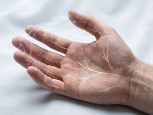 Menselijke hand met gevisualiseerde zenuwprikkeling als gouden en blauwe elektrische vonkjes op vingertops en handpalm