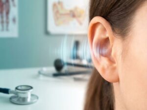 Close-up van menselijk oor met blauwe geluidsgolven in medische omgeving met stethoscoop