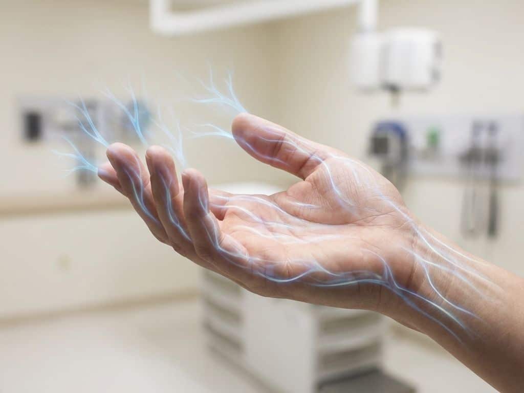 tingling-hand-zenuwbanen-symptomen-medisch.jpg Menselijke hand met blauwe lichtpatronen die zenuwbanen en tintelingen visualiseren tegen witte medische achtergrond