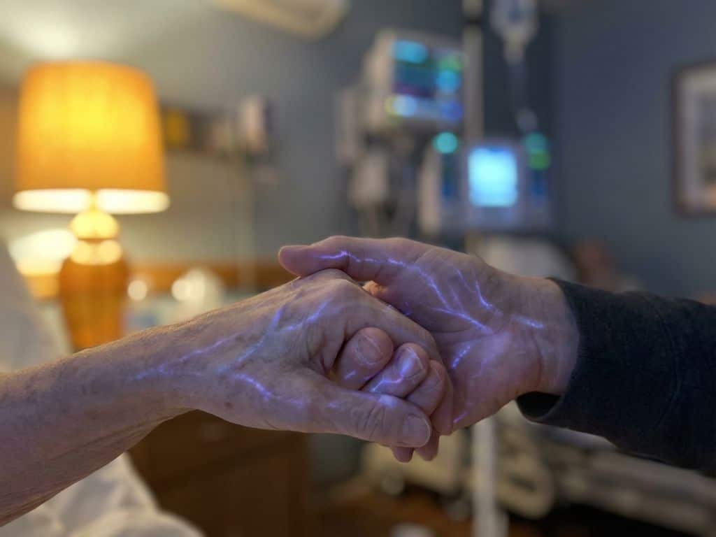 tingling-handen-zenuwpijn-genezing-therapie.jpg Twee handen raken elkaar voorzichtig aan met blauw-paarse lichtstralen uit vingertips, tintelende sensaties voorstellend