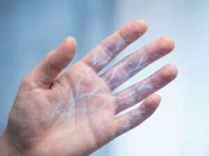 Hand met verlichte zenuwbanen in blauw en wit tegen medische achtergrond, tintelende vingertopjes zichtbaar